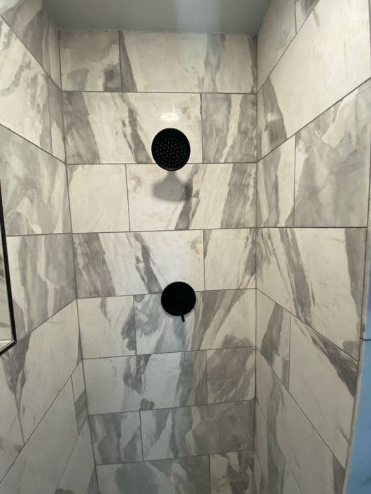 Marble-look shower tile with black fixtures