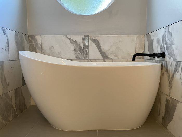 Freestanding tub with marble-look tile wainscot